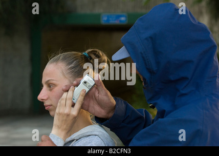 Weißen männlichen Angreifer Tassen junge weiße weibliche Opfer von ihrem Handy Stockfoto