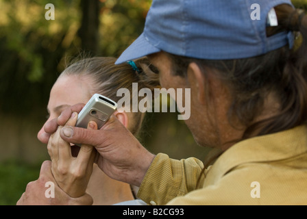 Weißen männlichen Angreifer Tassen junge weiße weibliche Opfer von ihrem Handy Stockfoto