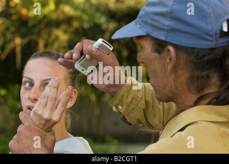 Weißen männlichen Angreifer Tassen junge weiße weibliche Opfer von ihrem Handy Stockfoto