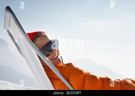 Person sitzt in Liegestuhl im Schnee Stockfoto