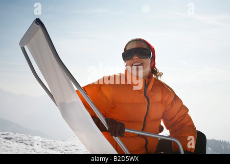 Frau im Liegestuhl auf Schnee Stockfoto