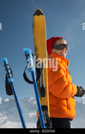 Von Ski und Skistöcke lächelnde Frau Stockfoto