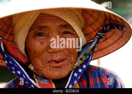 Eine Frau trägt einen traditionellen konischen Hut in Hoi An Vietnam. Sie rudert ein Boot um Fisch zum Fisch Kai zu liefern. Stockfoto