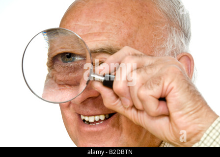 Humorvolle Horizontal Nahaufnahme Portrait ein älterer Herr mit einer großen Lupe oder Hand Objektiv nah an seinem Auge Stockfoto