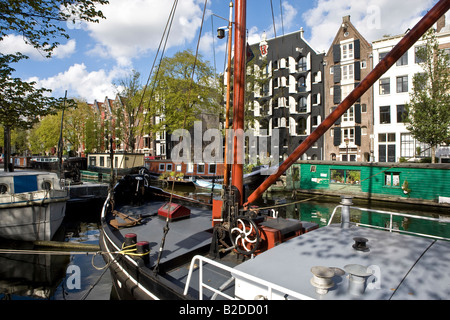 Canalside Szene in Amsterdam, Nordholland, Niederlande. Gegensätzlichen Stile in das Boot und gehobenen Wohnungen zu leben Stockfoto