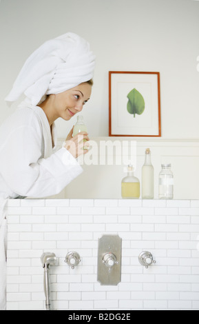 Junge Frau riechen Badeöl im Badezimmer. Stockfoto