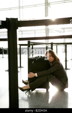 Müde Geschäftsfrau umarmt Gepäck im Flughafen. Stockfoto