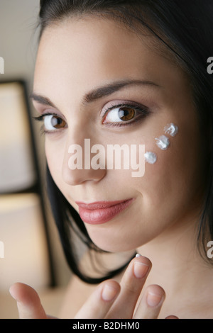 Junge Frau Gesichtscreme auftragen. Stockfoto
