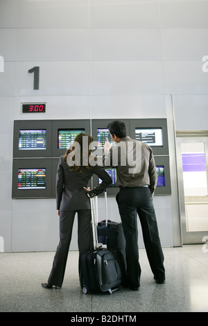 Geschäftsleute, die Bildschirme der Abflug am Flughafen zu betrachten. Stockfoto