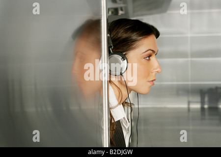 Junge Geschäftsfrau Kopfhörer im Flughafen anhören. Stockfoto