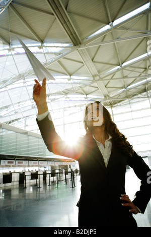 Junge Geschäftsfrau werfen Papierflieger im Flughafen. Stockfoto