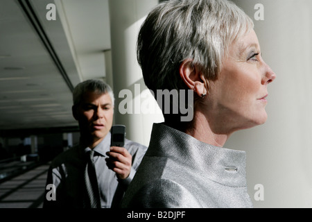 Reife Frau suchen Fenster am Flughafen mit Hintermann. Stockfoto