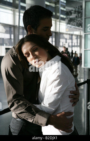 Junges Paar umarmt im Flughafen. Stockfoto