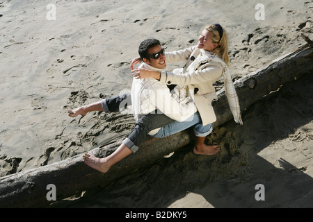 Junges Paar auf Log am Strand entspannen. Stockfoto