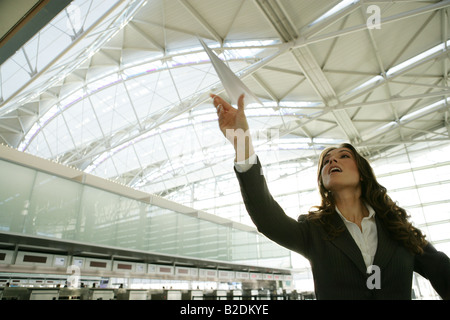 Junge Geschäftsfrau werfen Papierflieger im Flughafen. Stockfoto