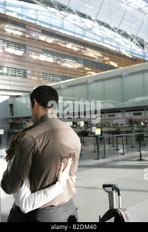 Junges Paar umarmt im Flughafen. Stockfoto