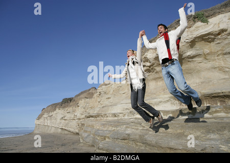 Junges Paar von Klippe am Strand zu springen. Stockfoto