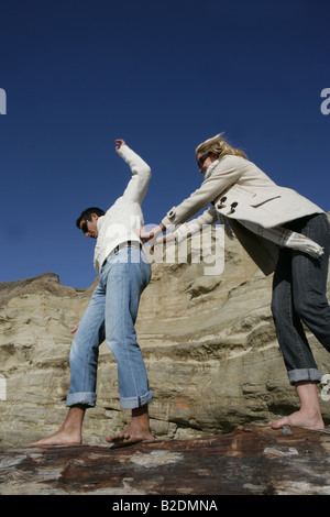 Junge Paare, die auf Klippen am Strand. Stockfoto