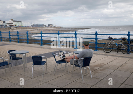 Einsame Radfahrer sitzen auf Porthcawl Strandpromenade mit Blick auf die Severn Mündung auf einem windigen Nachmittag im Juli 2008 Stockfoto