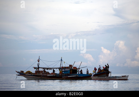 Fischer laden ihr Boot am Abend an der Mansalay Bay im Mansalay, Oriental Mindoro, Philippinen. Stockfoto