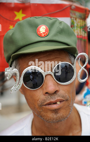 Chinesische Fan mit Mao Abzeichen und Brillen 2008 Gestaltung und Drachen außerhalb der Olympic Green in Peking. 27. Juli 2008 Stockfoto