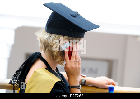 Universität von Sussex Sommer Promotionen an der Brighton Dome - Absolventin glücklich auf dem Handy nach der Zeremonie. Stockfoto