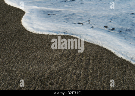 Eine Welle angespült wird auf dem grauen Sand Habushiura Beach Niijima, Izu-Inseln. Stockfoto