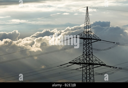 Hohe Spannung Strom Stromkabel und Pylon gegen sonnendurchflutete Wolken Himmel Stockfoto
