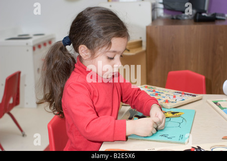 4 Jahre alte Pre-Schulmädchen sitzen an einem Tisch eine Puzzle zu tun Stockfoto