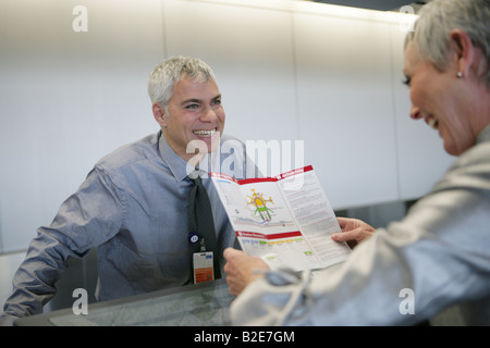 Glücklich Reife Frau Broschüre am Flughafen Check-in Schalter zu betrachten. Stockfoto