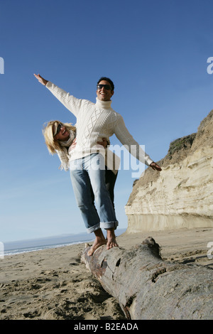 Junges Paar balancing auf Baumstamm am Strand. Stockfoto