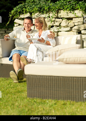 Paar Essen und lächelnd auf couch Stockfoto