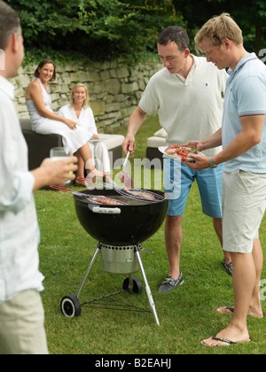Zwei Männer, die Zubereitung von Fisch auf Barbecue-Grill im Garten Stockfoto