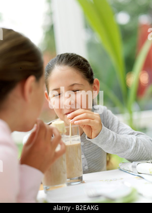Zwei Mädchen trinken Schokomilch mit Stroh Stockfoto