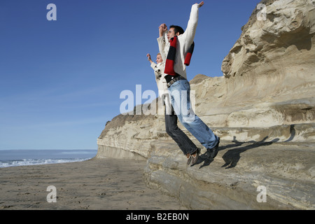 Junges Paar von Klippe am Strand zu springen. Stockfoto