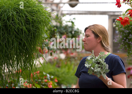 Frau macht ein lustiges Gesicht entscheiden, beim Kauf einer Pflanze im Gewächshaus eines Kindergartens in Nampa, Idaho Stockfoto