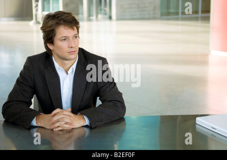 Geschäftsmann, sitzen an einem Schreibtisch mit seinen Händen umklammert Stockfoto