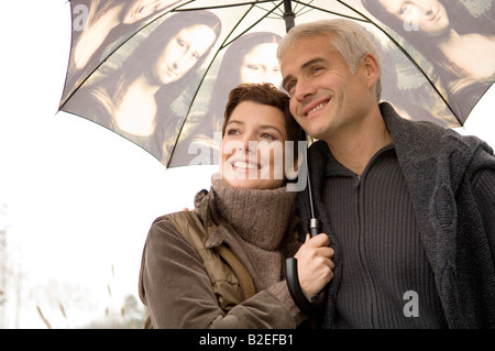 Nahaufnahme einer Mitte erwachsenen Frau und einem reifen Mann unter einem Regenschirm Stockfoto