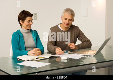 Reifer Mann und Mitte Erwachsene Frau auf einem Laptop arbeiten und halten eine Kreditkarte Stockfoto