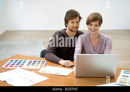 Mitte erwachsener Mann und eine junge Frau mit einem Laptop und lächelnd Stockfoto