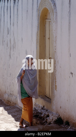 Eine Harari Mädchen geht in einer schmalen gepflasterten Straße von den mittelalterlichen Mauern umgebene Stadt Harar.  Einmal ein unabhängiger Stadtstaat. Stockfoto