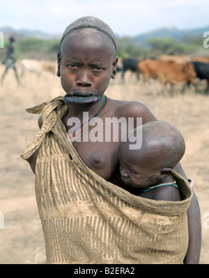 Mursi-Mutter und Kind.  Die Mutter trägt eine große Ton Mundlochplatte. Stockfoto