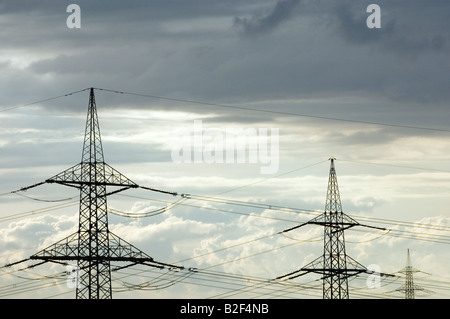 Hohe Spannung Strom Stromkabel und Pylonen gegen sonnendurchflutete Wolken Himmel Stockfoto
