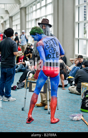 Ein Versammlungsteilnehmer, gekleidet wie eine ökologische Ermahnung seine blau gefärbte Haut bei Comic-Con International in San Diego berührt Stockfoto