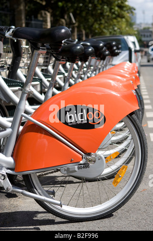 Zeile Bicloo Fahrräder in ihren Docking-Stationen und ein Radfahrer in Nantes, Frankreich (als Velib Fahrräder in Paris) Stockfoto