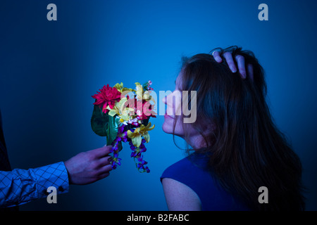 Frau riechen die Blüten angeboten, um sie von einem Mann s ausgestreckten arm Modell veröffentlicht Stockfoto