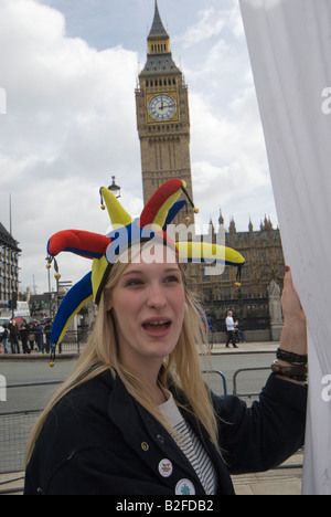 Junge Frau im Narren GAP und Big Ben in Parliament Square "Fossil Fools Day" Kundgebung gegen Klimawandel Stockfoto