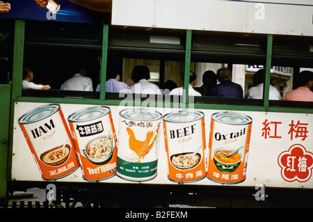 Plakate Werbung Dosen Suppe auf der Seite einen Zug mit Passagieren in Hongkong 1985 Stockfoto