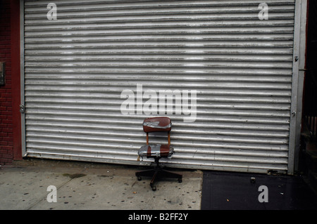 Distressed Bürostuhl vor Roll Tor des geschlossenen Stores in New York NY Stockfoto