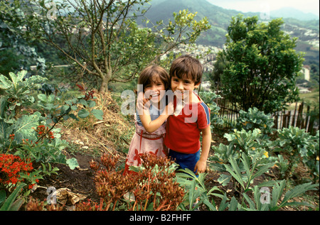 zwei lächelnde Kinder Ninos de Los Andes-Stiftung stehen im Garten Stockfoto